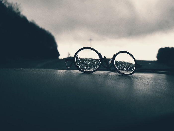 Close-up of eyeglasses on glass against sky