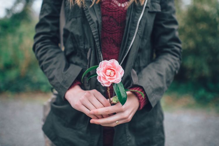 Midsection of young woman holding rose flower