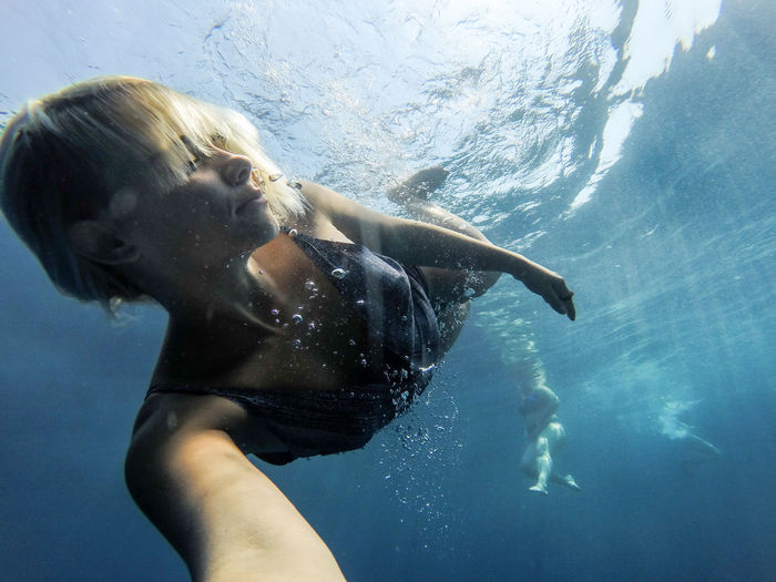 Close-up of young woman swimming underwater