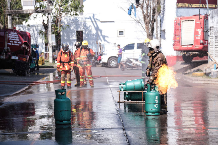 Firefighters standing on wet road against building