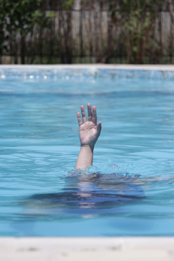 Cropped hand emerging from swimming pool