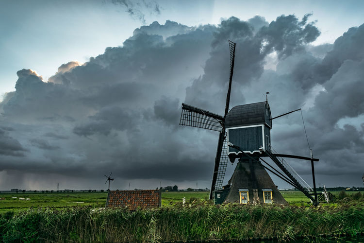 Windmill in dutch landscape with thunderstorm