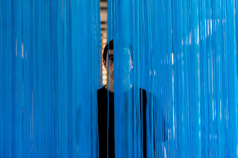 Portrait of man standing behind blue textile