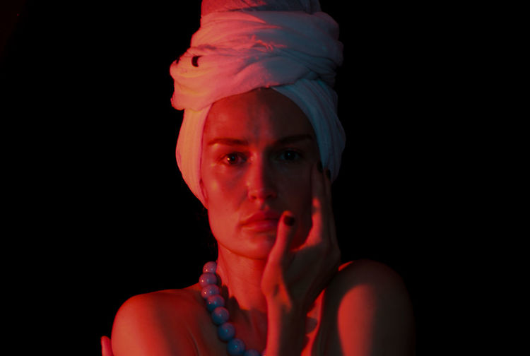 Close-up portrait of woman wearing turban against black background