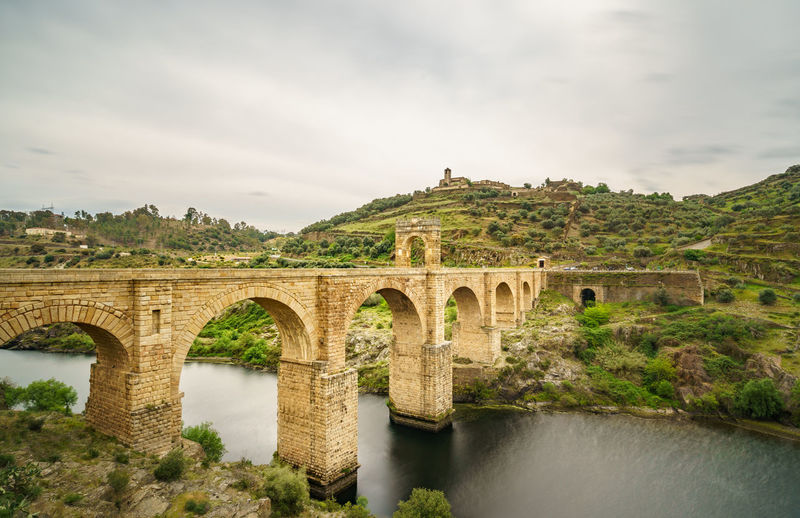 Arch bridge over river against sky