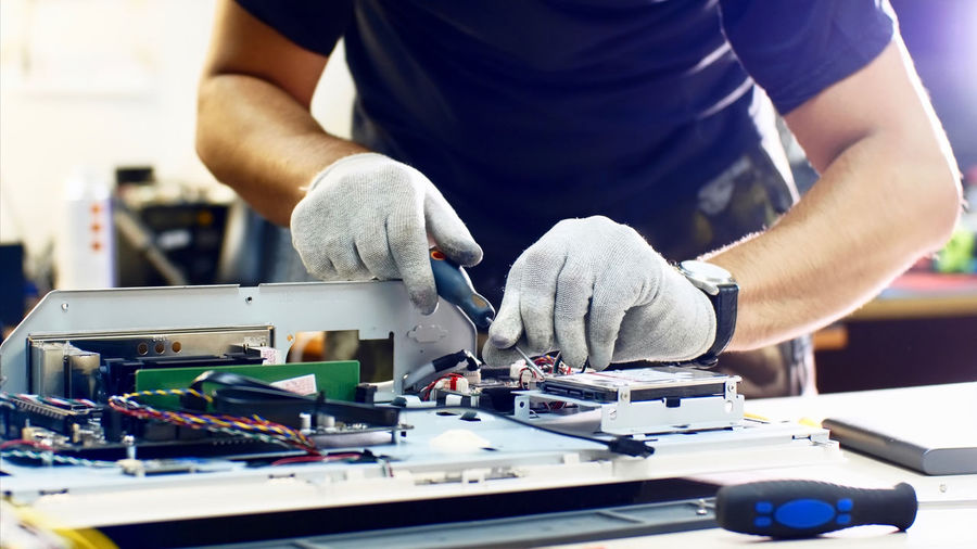Midsection of man repairing computer equipment on table