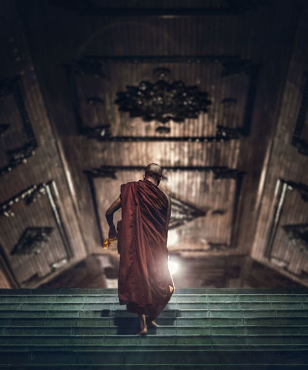 Rear view of monk walking on building