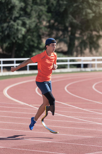 Young athlete with prosthetic leg running on sports track