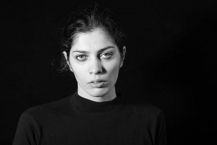 Portrait of sad woman over black background