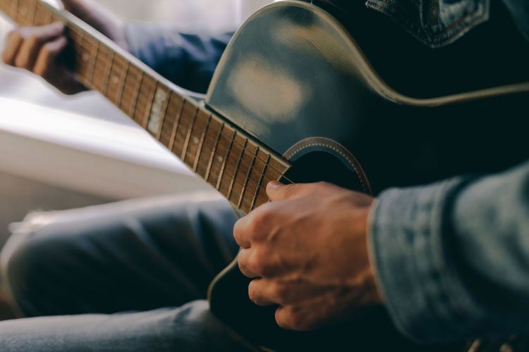 Midsection of man playing guitar