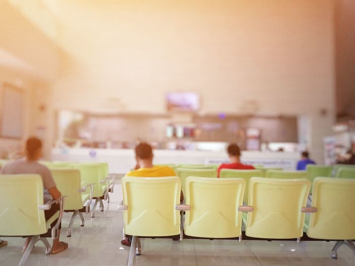 Rear view of people sitting on chairs in waiting room