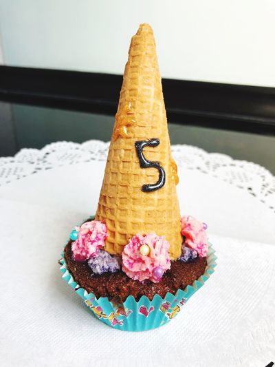 Close-up of cupcake with ice cream cone on table