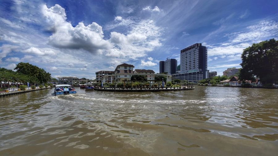 Scenic view of river by buildings against sky