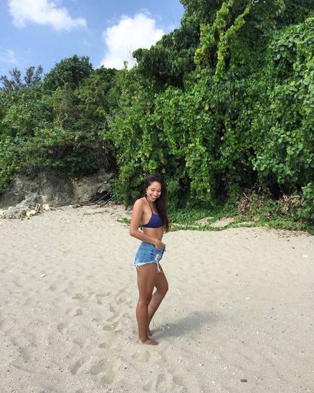 Side view of woman wearing bikini standing at beach
