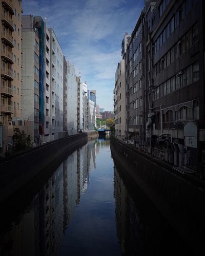 Canal amidst city against sky