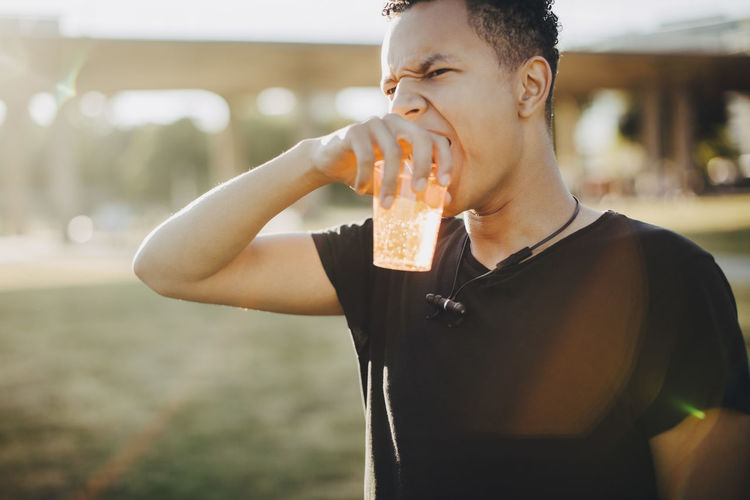Midsection of young man drinking water