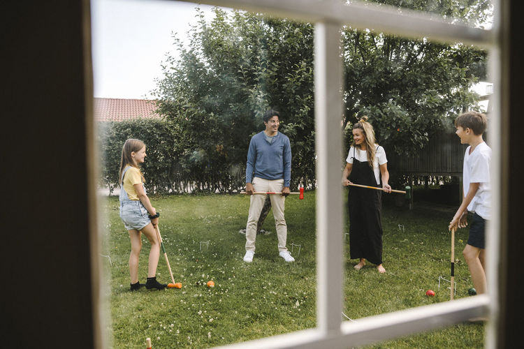 Happy family playing polo in front yard
