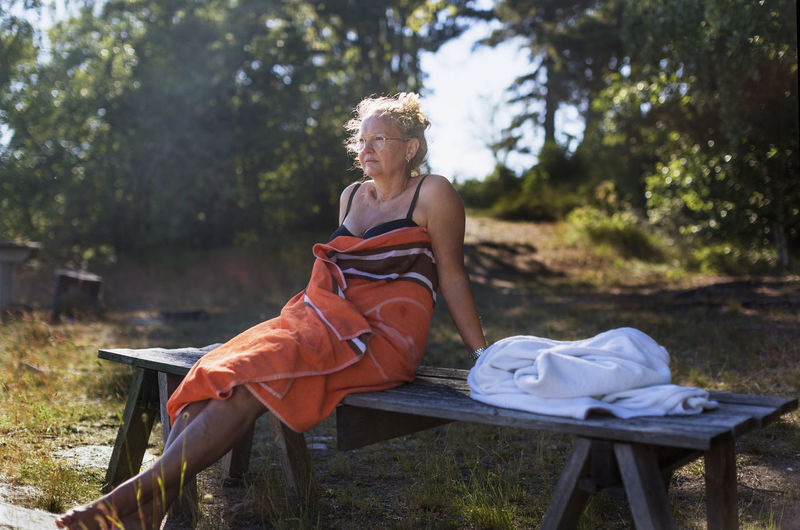 Woman wrapped in towel relaxing on bench