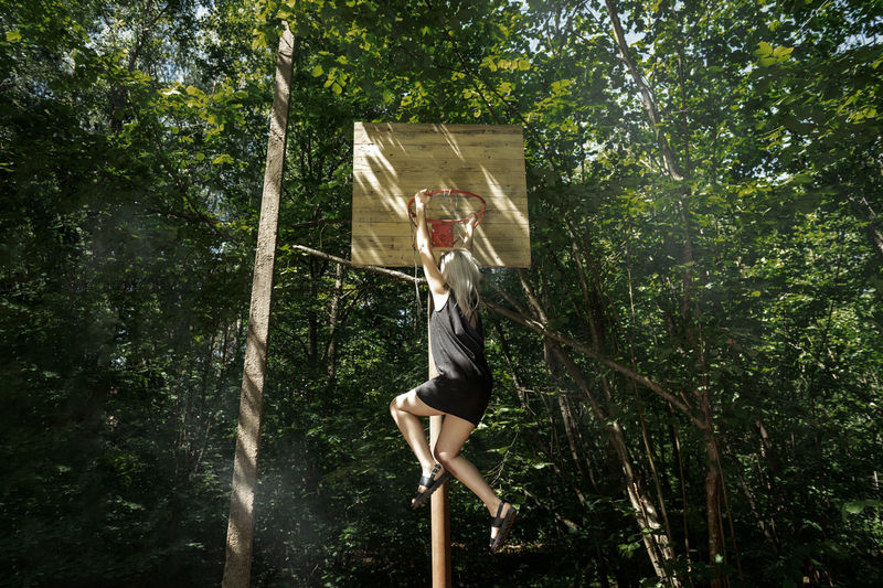 Woman hanging on basketball hoop