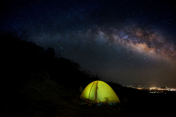 Illuminated tent on field against sky at night