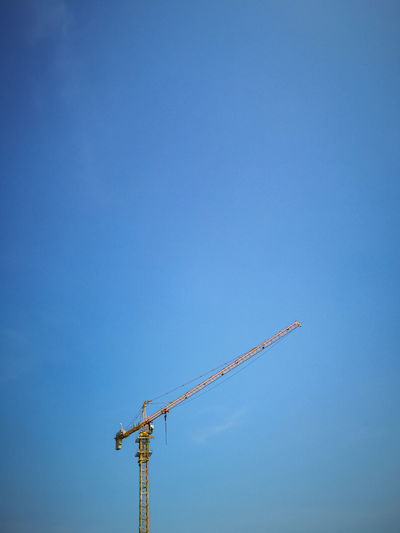 Low angle view of crane against blue sky