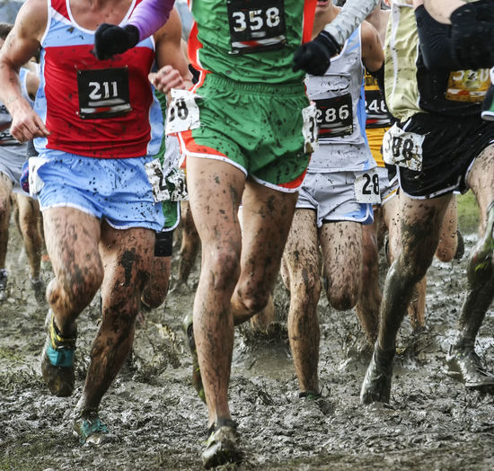 Runners racing a high school championship 5k in heavy mud with their spikes taped on with duct tape.