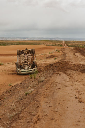 Upside down car that has flipped on a muddy dirt road in utah desert
