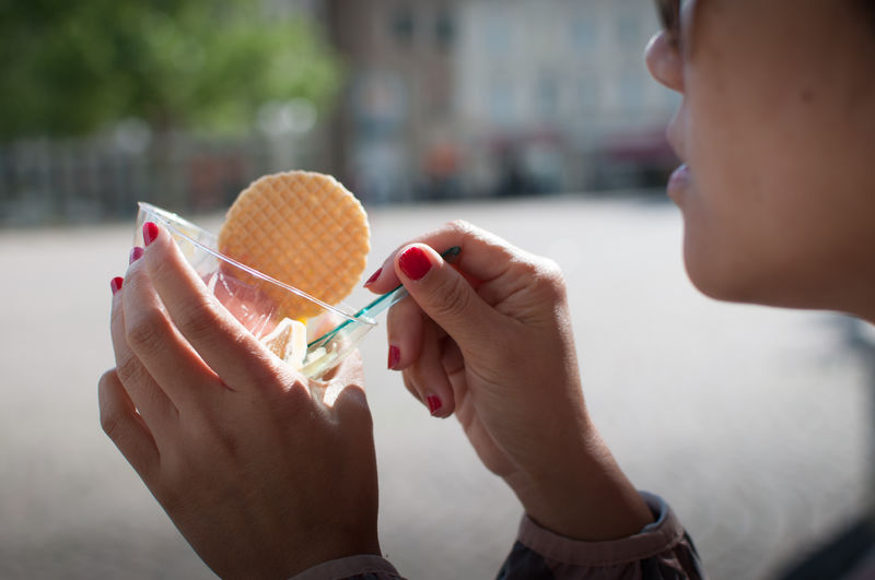 Close-up of woman eating dessert by street