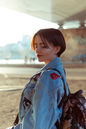 Young woman in denim jacket standing outdoors