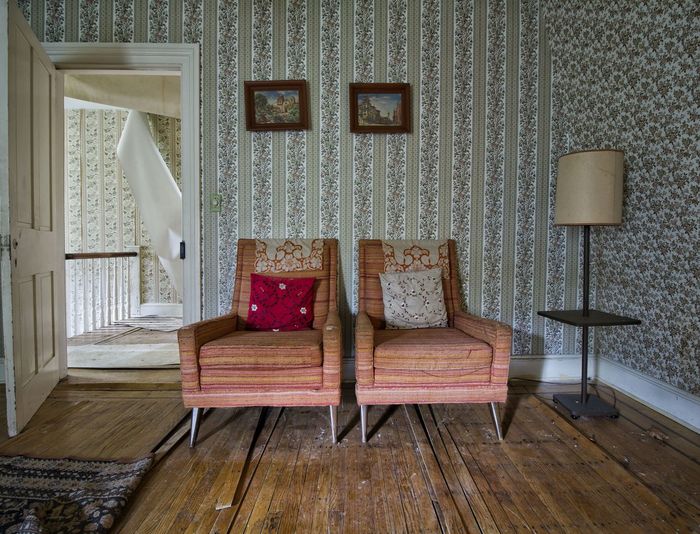 Empty chairs against wall at abandoned home