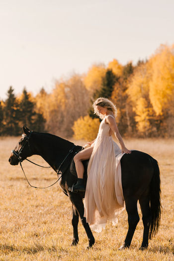 Woman riding horse on field