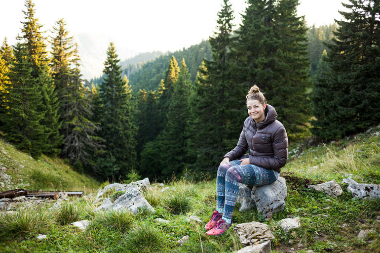Smiling woman sitting in forest during winter