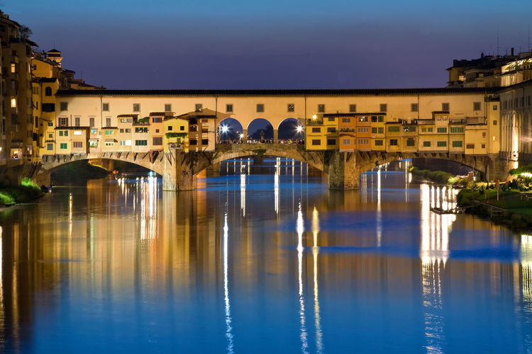 Arch bridge over river against buildings