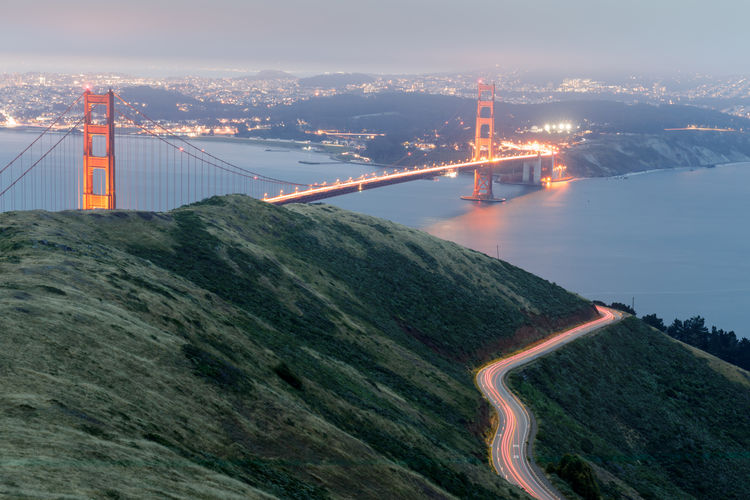 Car light trails and the golden gate bridge glowing at night