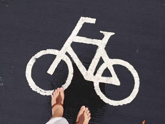 Low section of woman standing on bicycle lane