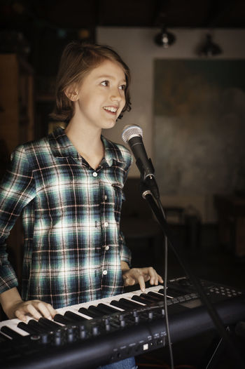Happy girl singing and playing piano
