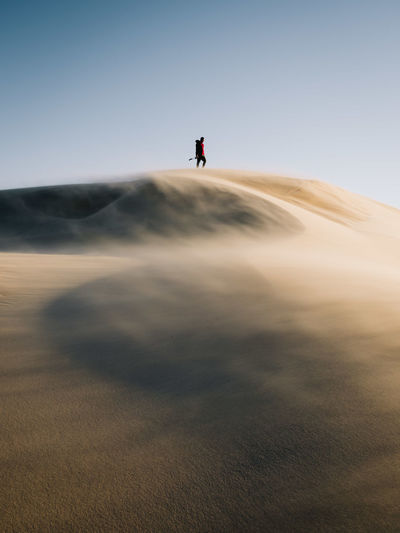 Man walking on desert against sky