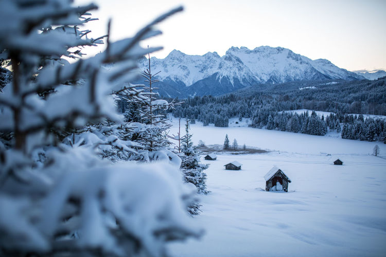 Scenic view of snow covered field and  barn with mountains against sky, bavaria, germany. 