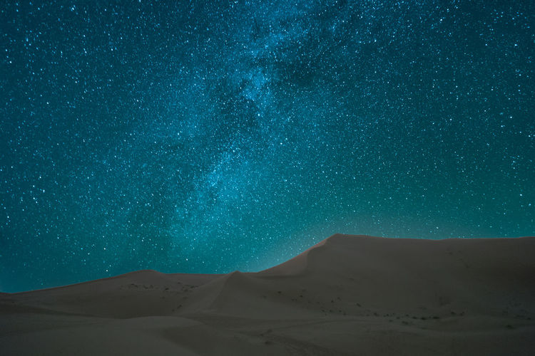 Scenic view of sand dunes in desert against sky at night