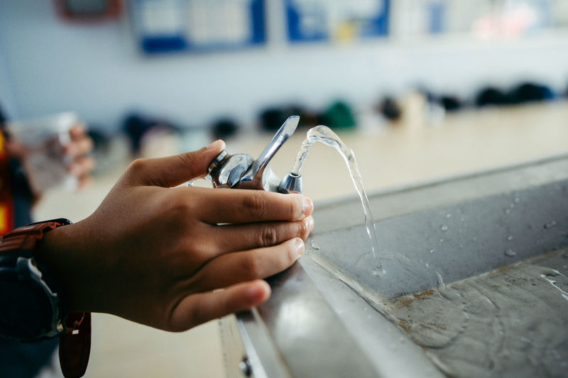 Close-up of hands holding faucet at drinking fountain