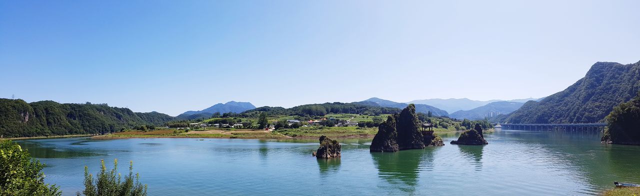 Scenic view of lake and mountains against clear blue sky