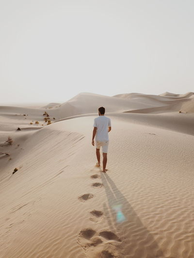 Rear view of man standing on sand dune