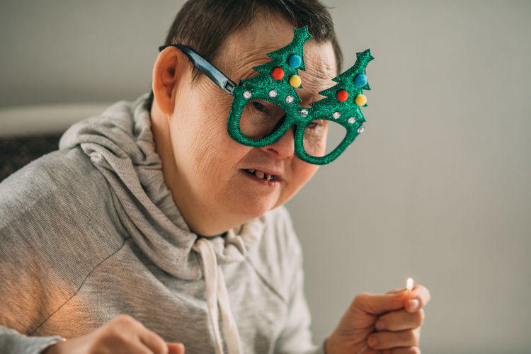 Elderly woman with down syndrome in funny christmas glasses with a garland in hands