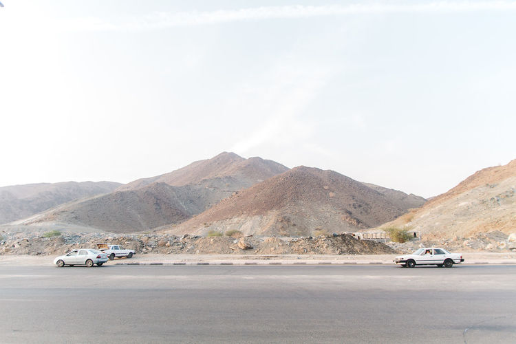 Cars on road in desert against sky