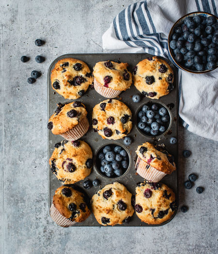 Overhead view of blueberry muffins in baking tin on concrete counter.