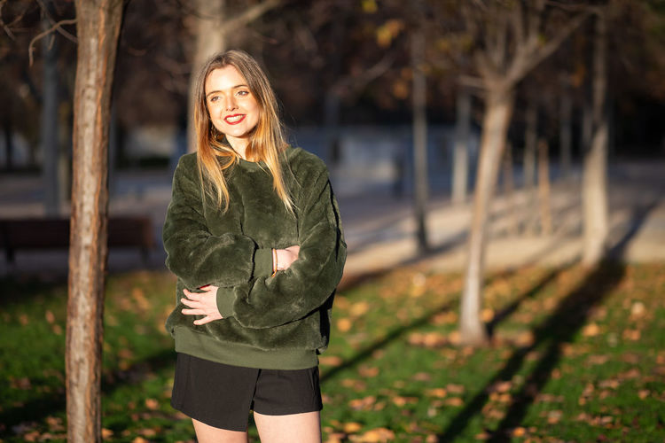 Smiling young woman standing at park during winter