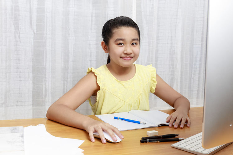 Portrait of smiling girl studying at table