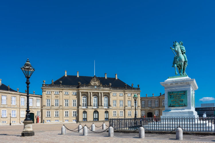 Statue and historical building against blue sky
