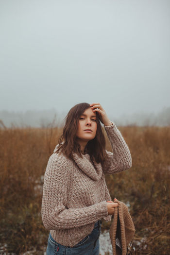 Women standing in a foggy late autumn winter field against sky with negative space