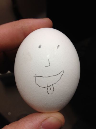 Cropped image of person holding white egg with face